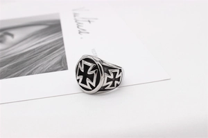 Close-up of vintage titanium steel biker ring featuring embossed Maltese cross and dark patina