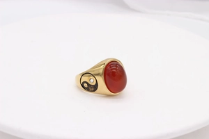 Macro detail of gold vintage ring featuring red gemstone and engraved Tai Chi symbol