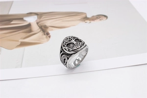 Detail view of vintage stainless steel ring with embossed tree of life and scroll patterns