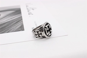 Macro shot of silver titanium steel biker ring with black iron cross embossed design