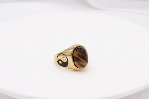 Detailed view of gold steel ring with oval tiger eye stone and yin-yang symbol