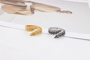 Detailed macro view of retro feather textures on gold and silver wing-shaped steel rings
