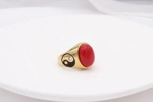 Macro shot of gold ring with red oval gemstone and yin yang side engraving details