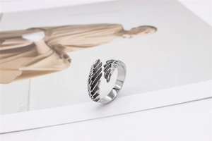 Macro detail showing vintage silver feather wings texture on a titanium steel ring