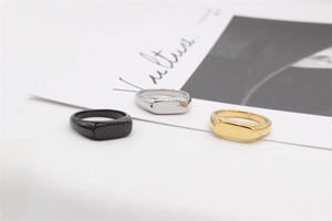 Lot de trois bagues sceau polies en noir, argent et or sur un magazine minimaliste