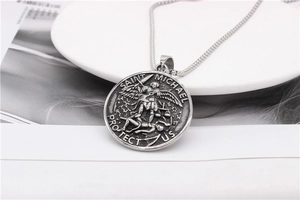 Détail macro du pendentif religieux Saint-Michel en acier argenté vintage sur blanc