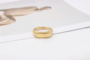 Gros plan d'une bague chevalière dorée minimaliste avec une finition miroir polie