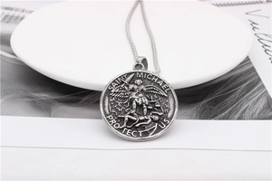 Détail macro du pendentif Saint Michel sur une chaîne à mailles gourmette en acier