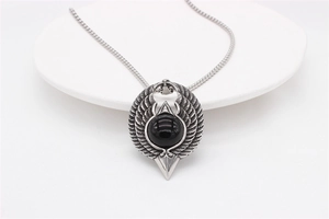 Macro detail of gothic eagle necklace featuring a large black gemstone and silver wings