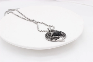 Macro detail of vintage eagle wing pendant with black gemstone and steel chain