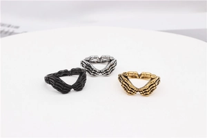 Detail view of gothic skull hands forming heart shape in black, silver, and gold steel