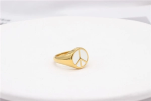 Macro shot of minimalist gold signet ring with white circular peace symbol inlay
