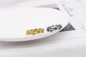 Detail of two punk-style skull and crossbones rings in gold and vintage silver finish