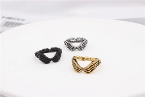 Detailed view of skull hand heart rings in black, silver, and gold vintage finishes