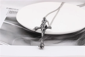 Detail of gothic silver cross necklace with bone texture on a white ceramic plate