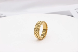 Detailed macro view of gold wide ring featuring textured scale relief and polished finish