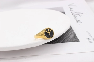 Detailed macro shot of a gold-plated signet ring with a black enamel peace symbol design