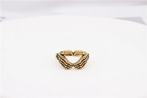 Macro shot of retro gold skull hands forming a heart shape on a vintage steel ring