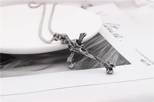 Detail of vintage silver bone cross pendant with rocky texture and punk style chain