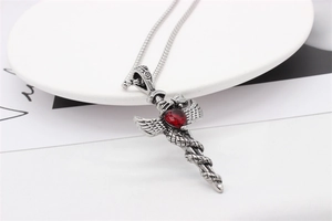 Macro detail of gothic sword pendant with red heart gem and silver wing textures