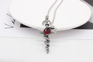 Macro detail of gothic pendant with red heart stone, snake-wrapped sword and wings