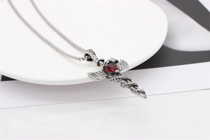 Macro detail of gothic pendant with silver wings, snake and red heart gemstone