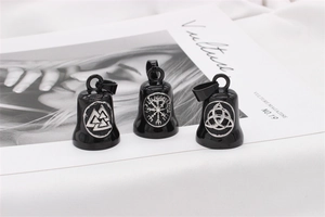 Detail of black Viking bell pendant with silver Celtic runes on magazine background