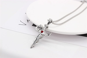 Detail shot of gothic silver dagger cross pendant with a vibrant red heart gem