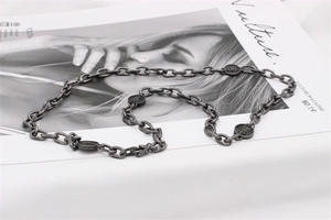 Vue détaillée du collier chaîne argenté rétro avec breloques sur magazine Vulture