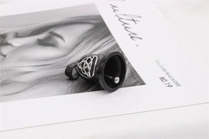 Detailed view of black Viking bell pendant with silver Celtic knot on fashion magazine