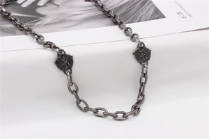 Detail of vintage oxidized titanium steel necklace featuring double angel relief pendants