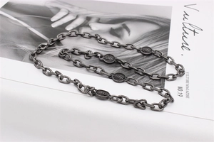 Détail d'un collier chaîne argenté vintage avec médaillons circulaires gravés