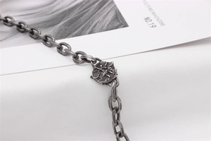 Close-up of vintage silver necklace featuring an angel relief medallion and textured links