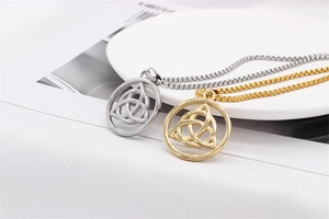 Detail view of gold and silver Viking Triquetra necklaces on polished stainless steel