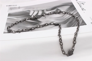 Detail of vintage silver titanium necklace with relief pendants on a magazine