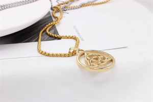 Detail of a gold Celtic Triquetra pendant on a square box chain over a white fabric background