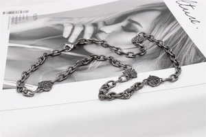 Macro detail of vintage silver steel chain necklace with circular embossed pendants and lobster clasp