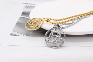 Detail of Viking Triquetra pendant necklaces in gold and silver on a white plate