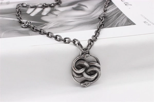 Macro shot of double-headed snake pendant with vintage steel finish on magazine backdrop