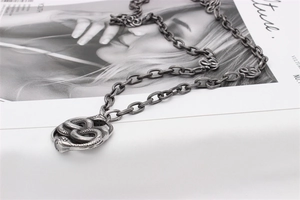 Close-up of vintage steel necklace featuring intertwined double snake knot design