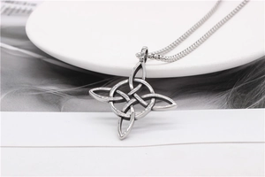 Detailed view of vintage silver Viking Witch's Knot pendant with a box chain on ceramic