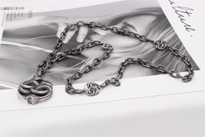 Detail of gothic stainless steel snake necklace with twin snake head pendants on paper