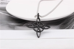 Detail of a black Celtic witch knot pendant on a silver ball chain with feathers