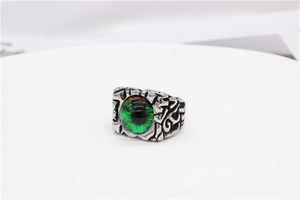 Macro view of gothic devil eye ring with green glass stone and silver embossed details
