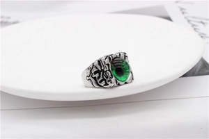 Detail of vintage silver dragon eye ring with green stone on a white ceramic plate