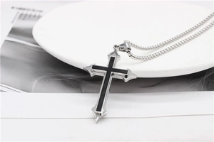 Detailed macro view of a silver cross pendant with black enamel inlay on a bead chain