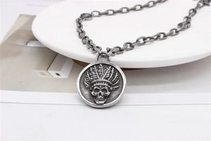 Détail d'un collier vintage argenté avec pendentif pièce de crâne indien sur assiette