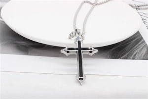 Detail of silver cross pendant with black enamel inlay on a delicate metal chain