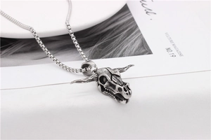 Close-up of a vintage bull skull pendant with detailed horns and a sturdy box chain