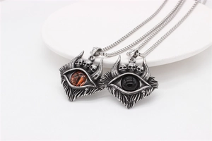 Détail macro de pendentifs gothiques en acier inoxydable avec crâne et œil maléfique